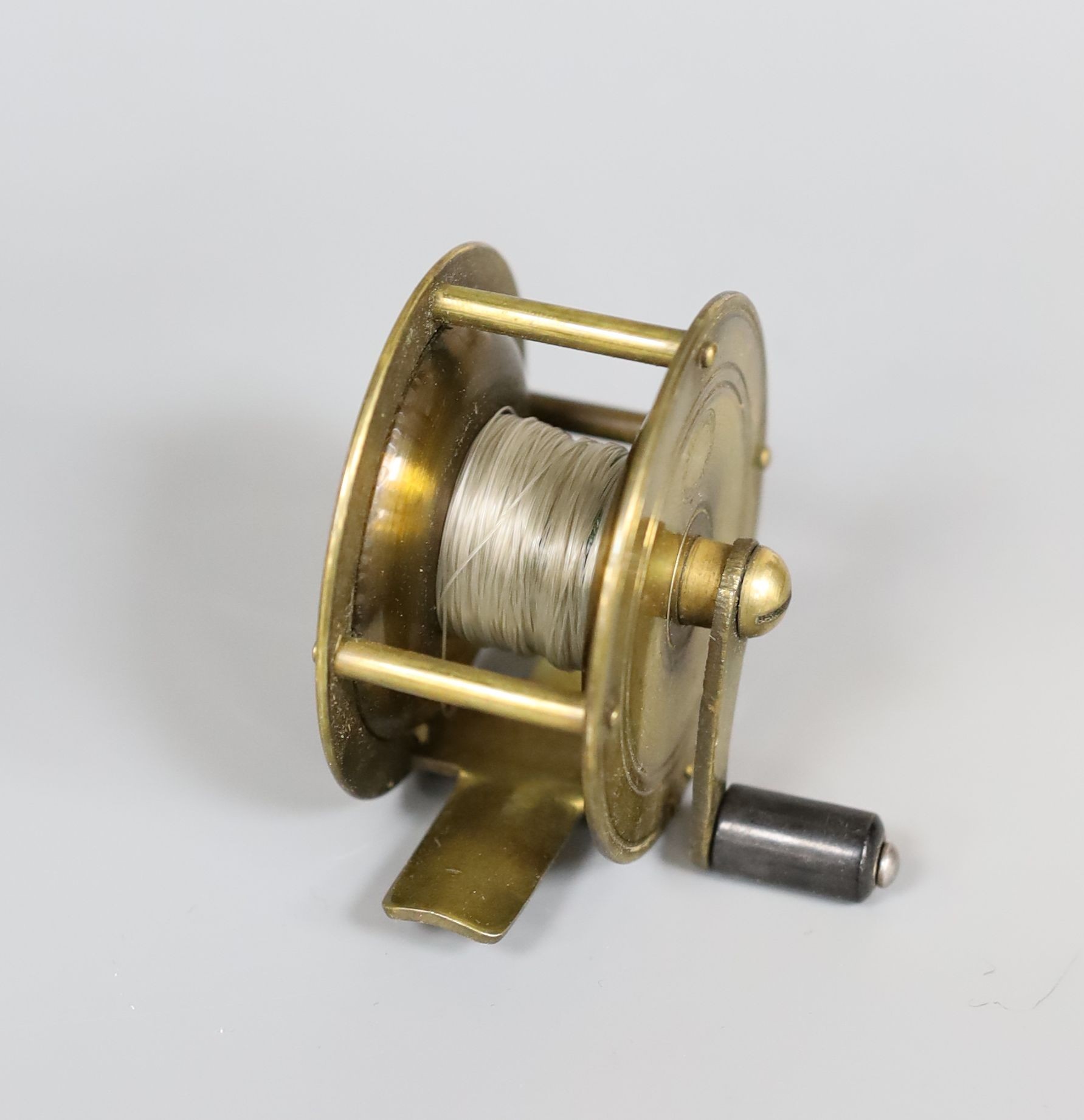 An Allcock brass fishing reel, 6cm. diam., in original box